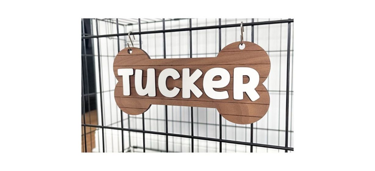 wooden, bone-shaped sign with a dog's name on it, hanging on a kennel